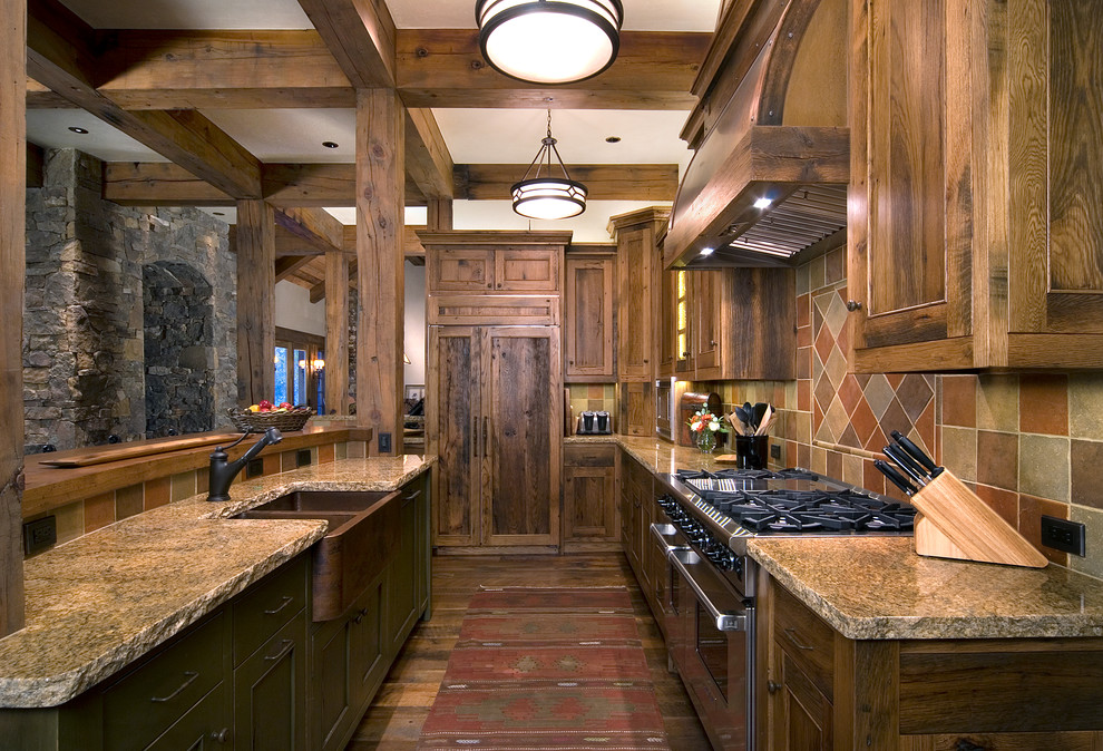 Photo of a rustic kitchen/diner in Denver with a belfast sink, shaker cabinets, distressed cabinets, granite worktops, terracotta splashback, integrated appliances, medium hardwood flooring and an island.