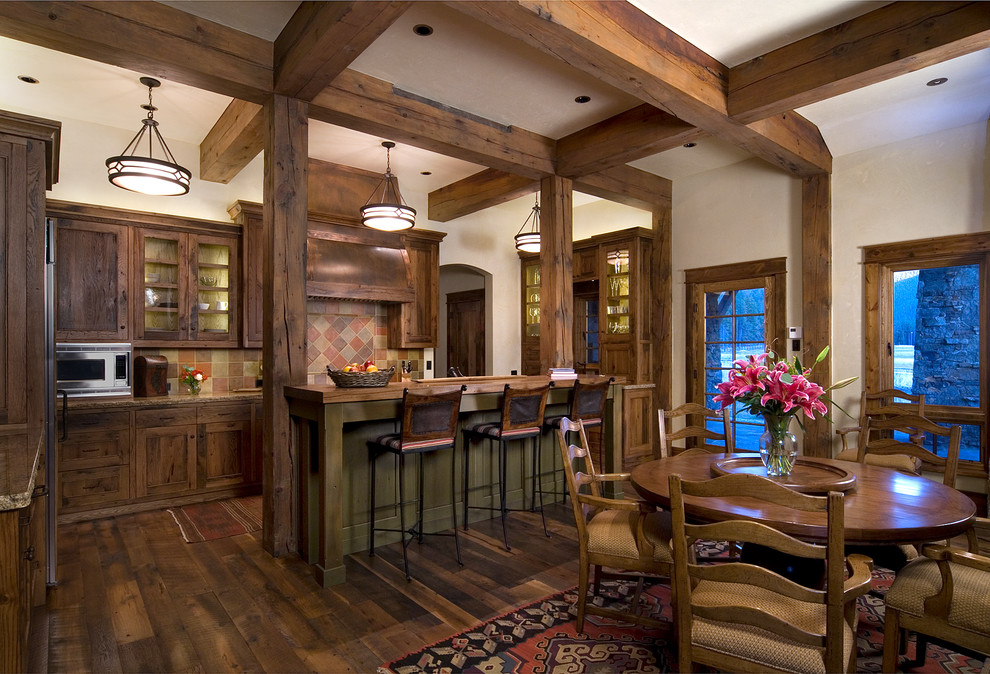 Example of a mountain style medium tone wood floor eat-in kitchen design in Denver with a farmhouse sink, shaker cabinets, distressed cabinets, granite countertops, terra-cotta backsplash, paneled appliances and an island