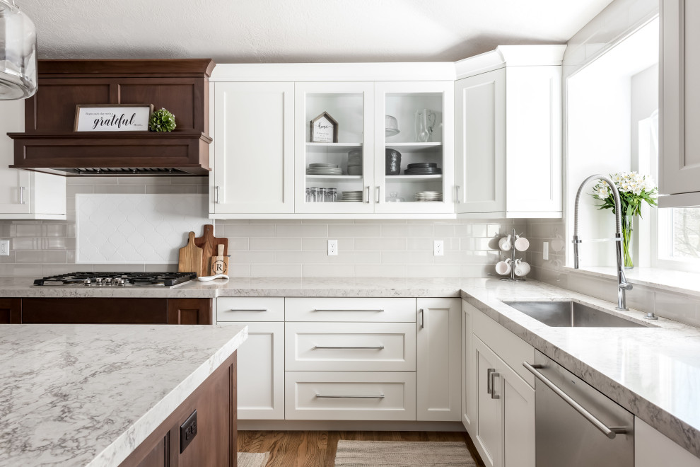 Idéer för mellanstora vintage flerfärgat kök, med en enkel diskho, luckor med infälld panel, vita skåp, bänkskiva i kvarts, flerfärgad stänkskydd, stänkskydd i keramik, rostfria vitvaror, mellanmörkt trägolv och en köksö