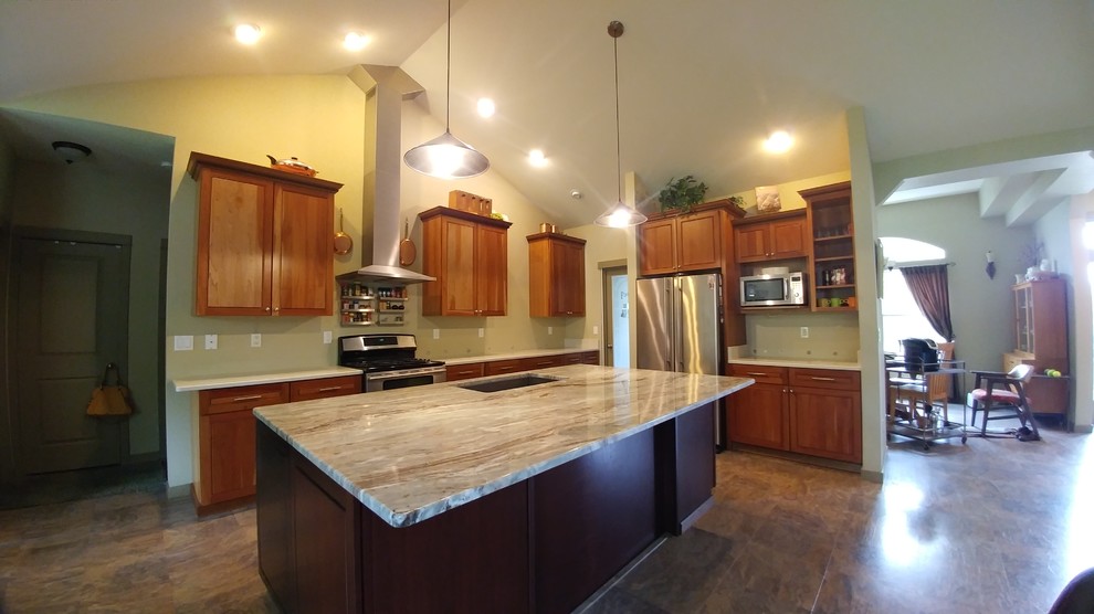 Klassisk inredning av ett avskilt, stort l-kök, med granitbänkskiva, stänkskydd i sten, en köksö, en undermonterad diskho, luckor med upphöjd panel, skåp i mellenmörkt trä, rostfria vitvaror, laminatgolv och brunt golv