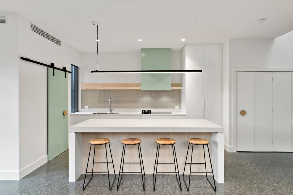 Offene, Zweizeilige Moderne Küche mit Küchenrückwand in Beige, Kücheninsel, Doppelwaschbecken, flächenbündigen Schrankfronten, weißen Schränken und grauem Boden in Melbourne