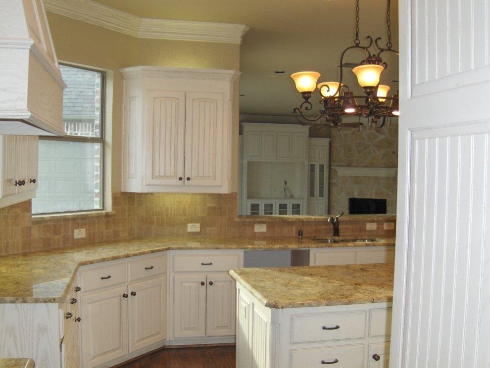 Example of a large southwest galley eat-in kitchen design in Dallas with a double-bowl sink, raised-panel cabinets, white cabinets, granite countertops, beige backsplash, stone tile backsplash and an island
