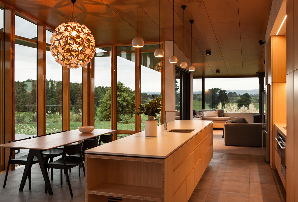 Zweizeilige, Mittelgroße Moderne Wohnküche mit profilierten Schrankfronten, hellen Holzschränken, Glasrückwand, Küchengeräten aus Edelstahl, Porzellan-Bodenfliesen und Kücheninsel in Auckland