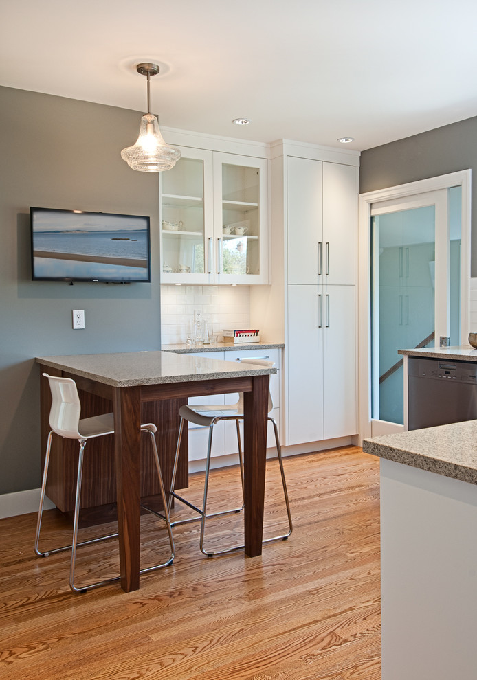 Enclosed kitchen - mid-sized contemporary u-shaped medium tone wood floor enclosed kitchen idea in Vancouver with an undermount sink, flat-panel cabinets, white cabinets, quartz countertops, white backsplash, subway tile backsplash, stainless steel appliances and a peninsula