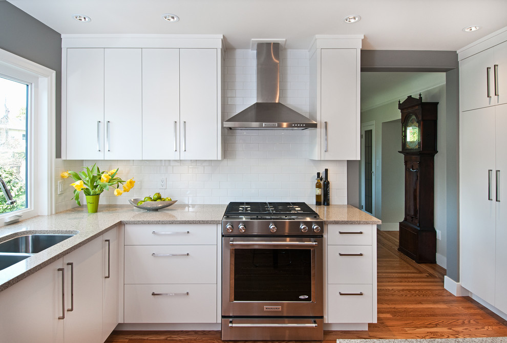 Inspiration for a mid-sized contemporary u-shaped medium tone wood floor enclosed kitchen remodel in Vancouver with an undermount sink, flat-panel cabinets, white cabinets, quartz countertops, white backsplash, subway tile backsplash, stainless steel appliances and a peninsula