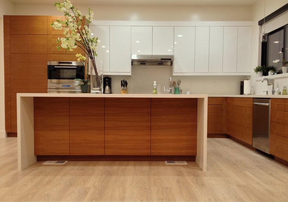 Foto de cocina contemporánea con fregadero bajoencimera, armarios con paneles lisos, puertas de armario de madera clara, encimera de cuarzo compacto y electrodomésticos de acero inoxidable