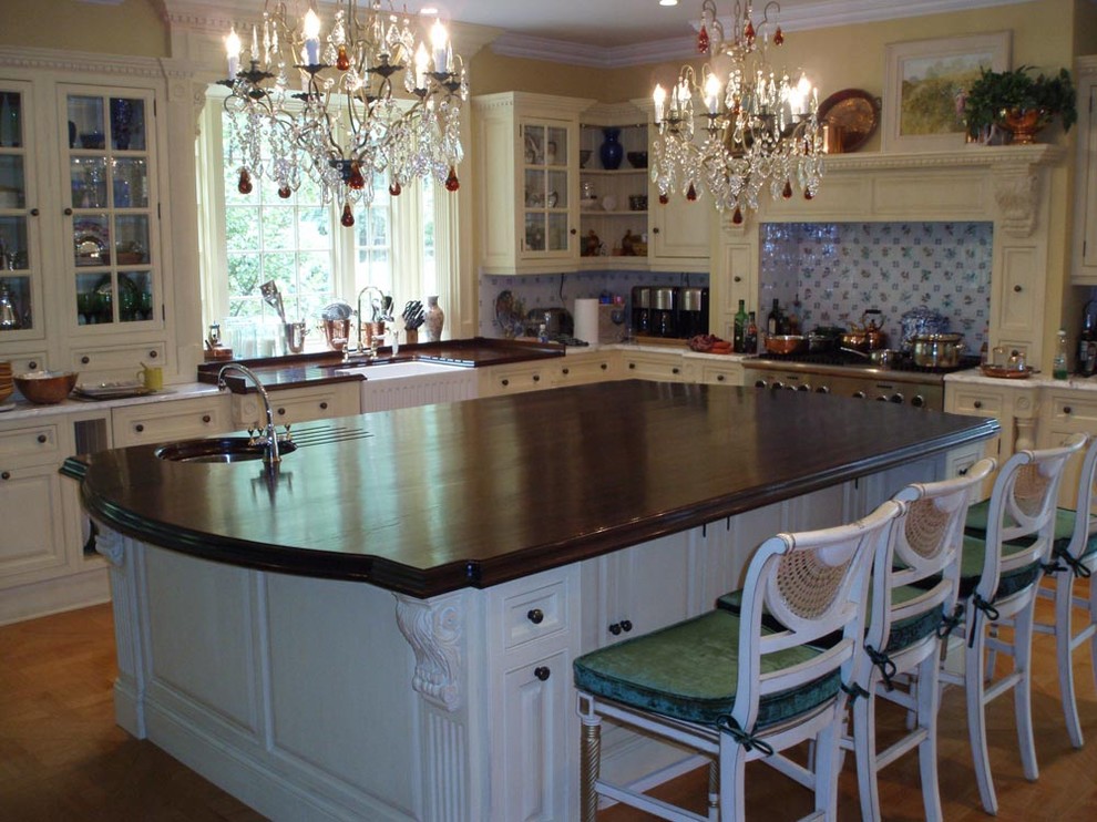 На фото: угловая кухня в классическом стиле с обеденным столом, врезной мойкой и деревянной столешницей с