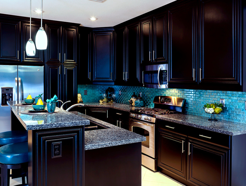 Inredning av ett klassiskt mellanstort kök, med en undermonterad diskho, luckor med upphöjd panel, svarta skåp, granitbänkskiva, blått stänkskydd, stänkskydd i glaskakel, rostfria vitvaror, klinkergolv i porslin och en köksö