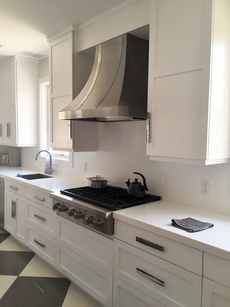Inspiration for a large urban kitchen in New York with a submerged sink, shaker cabinets, white cabinets, engineered stone countertops, white splashback, stone slab splashback, stainless steel appliances, ceramic flooring and an island.