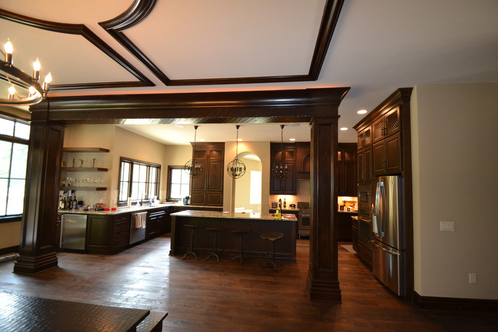 Foto på ett stort medelhavsstil kök, med en undermonterad diskho, luckor med upphöjd panel, skåp i mörkt trä, granitbänkskiva, beige stänkskydd, stänkskydd i stenkakel, rostfria vitvaror, mörkt trägolv och en köksö