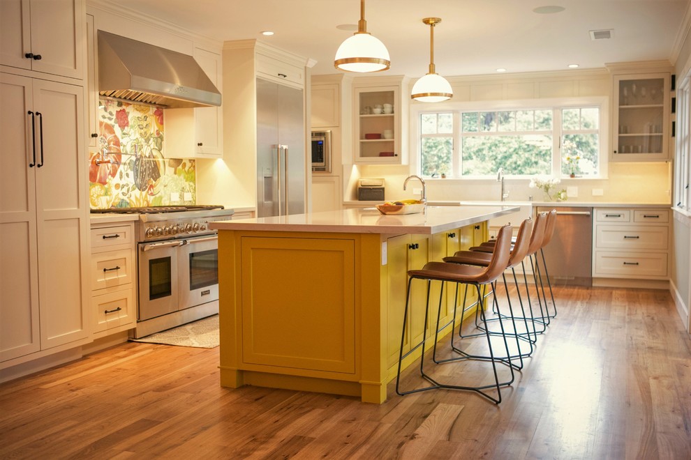 Eat-in kitchen - large farmhouse l-shaped medium tone wood floor and brown floor eat-in kitchen idea in San Francisco with a farmhouse sink, multicolored backsplash, glass sheet backsplash, stainless steel appliances, an island, shaker cabinets, white cabinets and quartzite countertops