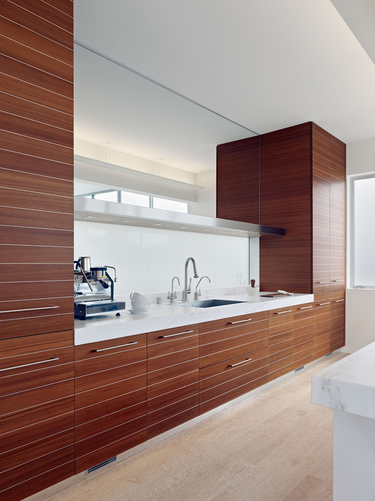 Imagen de cocina minimalista con electrodomésticos de acero inoxidable, armarios con paneles lisos y puertas de armario de madera oscura