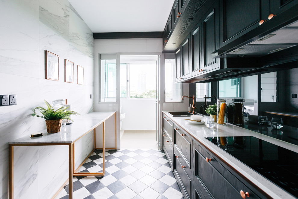 Example of a transitional single-wall black floor enclosed kitchen design in Singapore with a drop-in sink, recessed-panel cabinets, black cabinets, black backsplash, glass sheet backsplash, black appliances, a peninsula and beige countertops