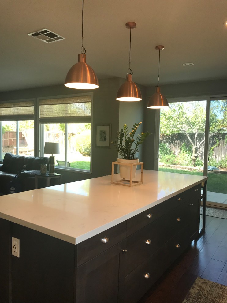 Inspiration for a large contemporary open plan kitchen in Los Angeles with a double-bowl sink, shaker cabinets, white cabinets, quartz worktops, grey splashback, glass tiled splashback, stainless steel appliances, medium hardwood flooring, an island and brown floors.