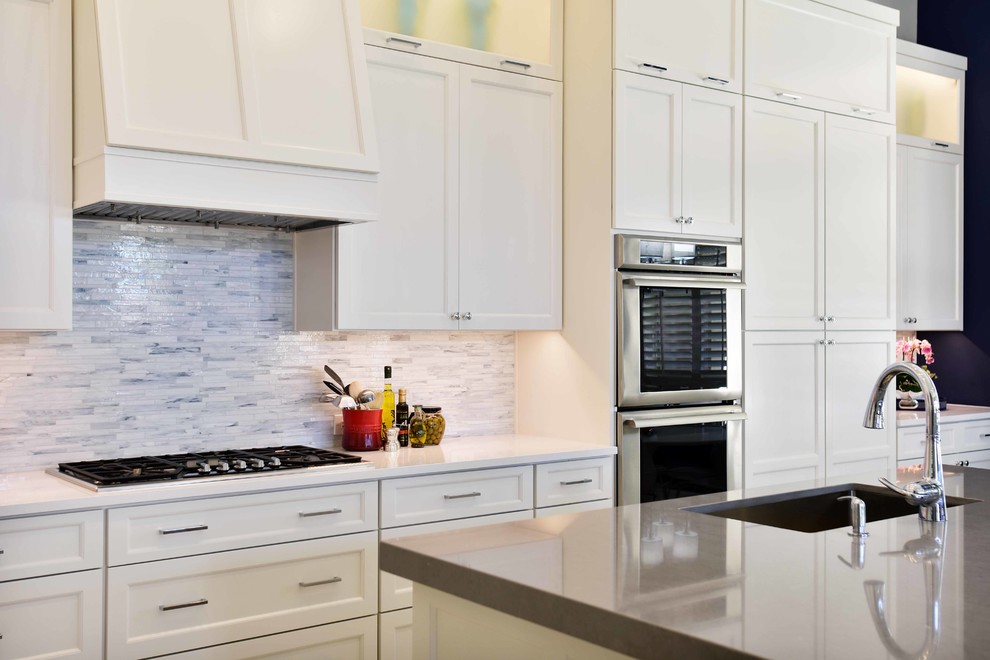 Idéer för att renovera ett stort vintage grå grått kök, med en undermonterad diskho, luckor med infälld panel, vita skåp, bänkskiva i kvarts, vitt stänkskydd, stänkskydd i stenkakel, rostfria vitvaror, klinkergolv i porslin, en köksö och beiget golv