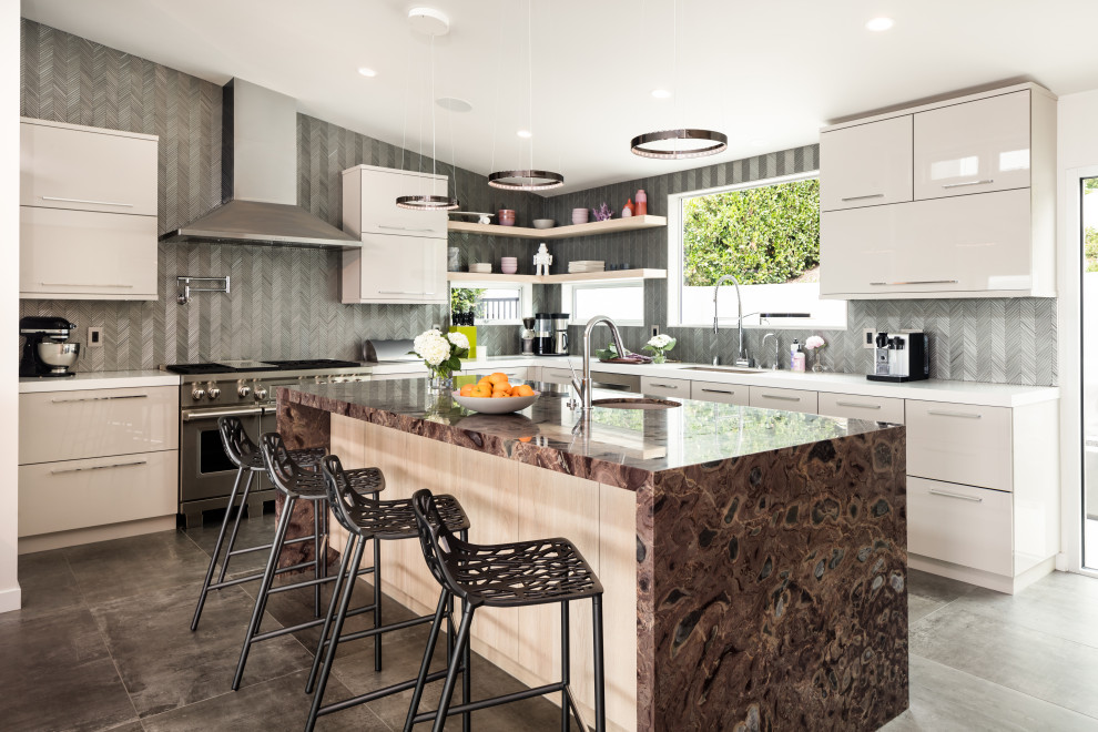 Example of a large trendy u-shaped porcelain tile and gray floor open concept kitchen design in Orange County with a single-bowl sink, flat-panel cabinets, beige cabinets, quartzite countertops, glass tile backsplash, stainless steel appliances, an island, gray backsplash and multicolored countertops