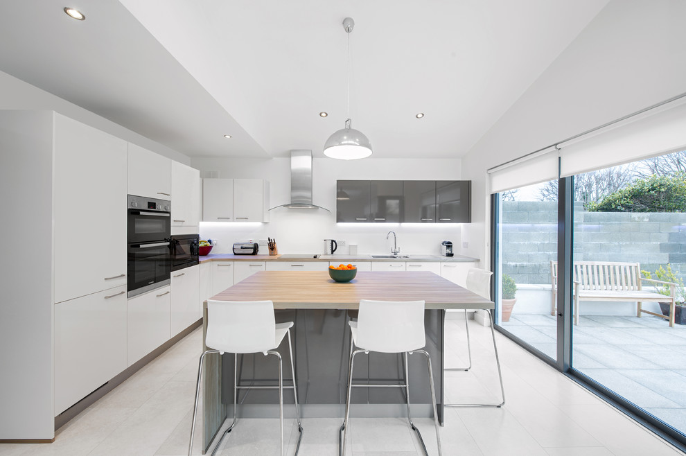 Mittelgroße Moderne Küche in L-Form mit weißen Schränken, Kücheninsel, flächenbündigen Schrankfronten, Küchenrückwand in Weiß und schwarzen Elektrogeräten in Dublin