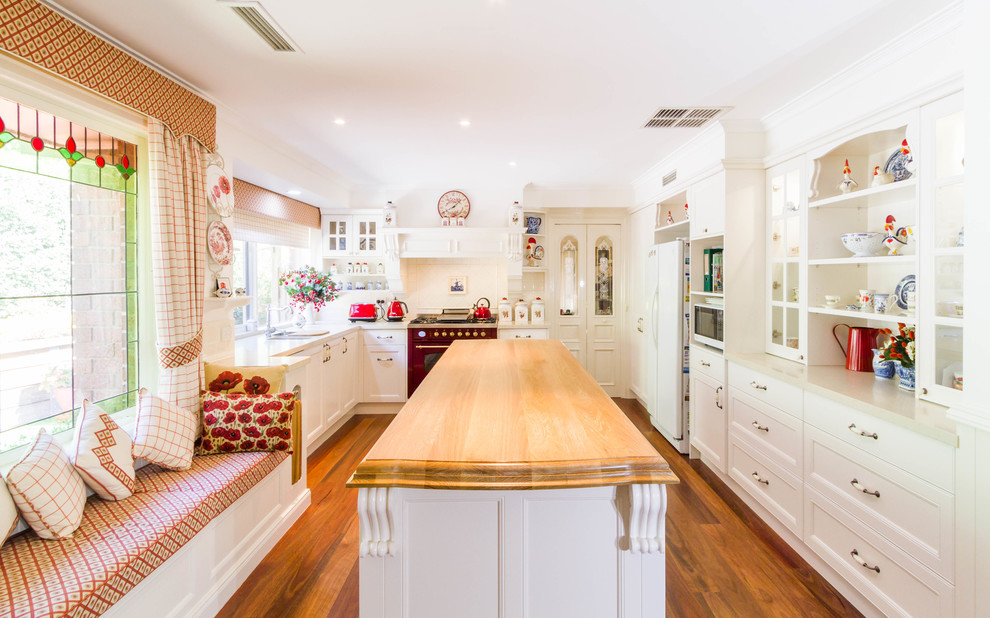 Bild på ett avskilt, stort lantligt u-kök, med en undermonterad diskho, skåp i shakerstil, vita skåp, träbänkskiva, vitt stänkskydd, stänkskydd i keramik, färgglada vitvaror, mellanmörkt trägolv och en köksö