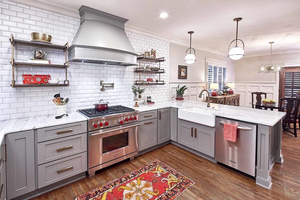 Bild på ett mellanstort vintage vit vitt kök, med en rustik diskho, skåp i shakerstil, grå skåp, marmorbänkskiva, vitt stänkskydd, stänkskydd i tunnelbanekakel, rostfria vitvaror, mellanmörkt trägolv, en halv köksö och brunt golv