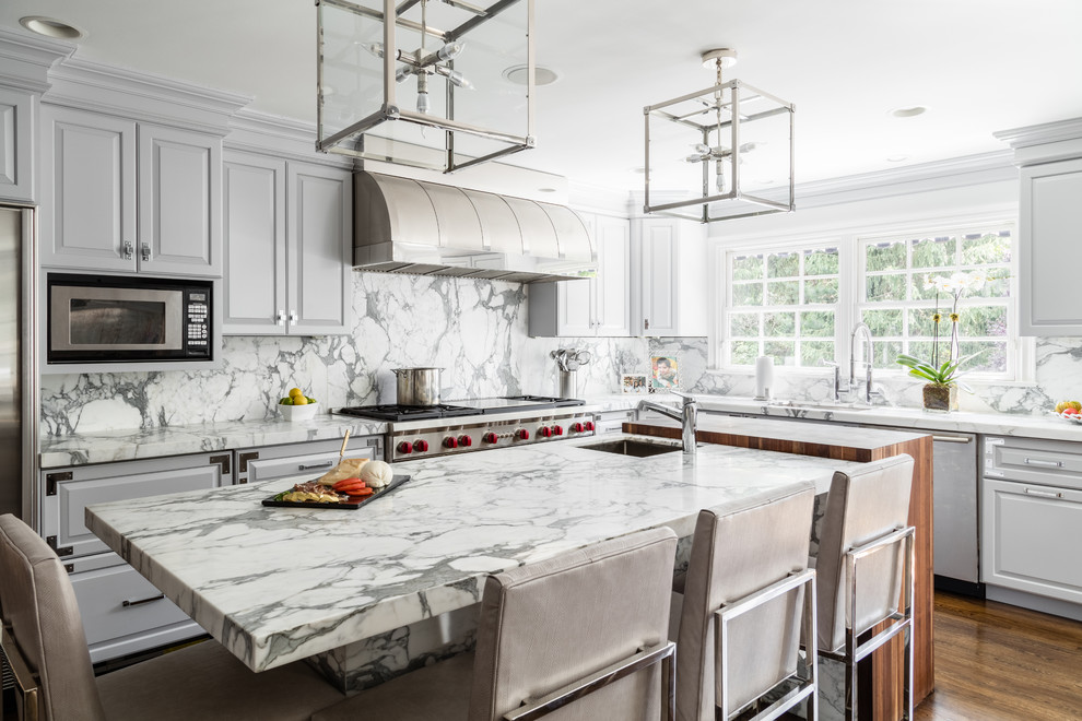 Example of an eclectic dark wood floor and brown floor eat-in kitchen design in New York with a single-bowl sink, raised-panel cabinets, white cabinets, marble countertops, white backsplash, stone slab backsplash, stainless steel appliances and an island