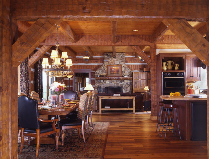Cette photo montre une grande cuisine américaine montagne en U et bois brun avec un placard avec porte à panneau surélevé, un plan de travail en granite, un sol en bois brun et îlot.