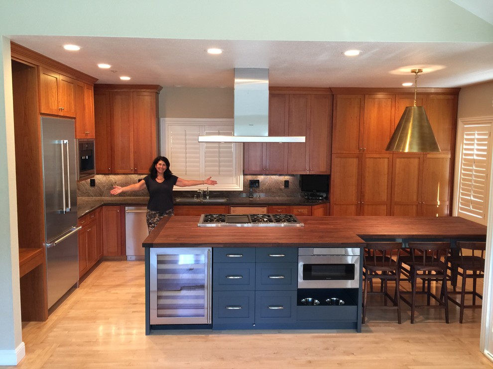 Modern inredning av ett mellanstort brun brunt kök, med en undermonterad diskho, skåp i shakerstil, skåp i mellenmörkt trä, träbänkskiva, grönt stänkskydd, rostfria vitvaror, ljust trägolv, en köksö och beiget golv