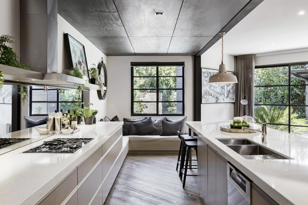 Inspiration for an industrial kitchen in Melbourne with engineered stone countertops, mirror splashback, stainless steel appliances, light hardwood flooring, an island and white worktops.