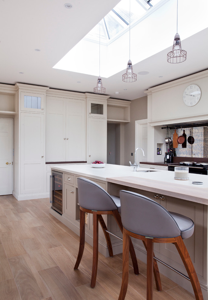 This is an example of a traditional l-shaped kitchen/diner in Dublin with a submerged sink, shaker cabinets, composite countertops, black appliances, medium hardwood flooring and an island.