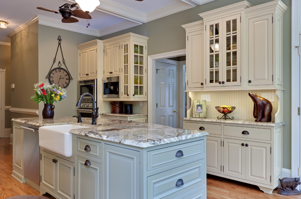 Modelo de cocina clásica con armarios con rebordes decorativos, fregadero sobremueble y puertas de armario beige