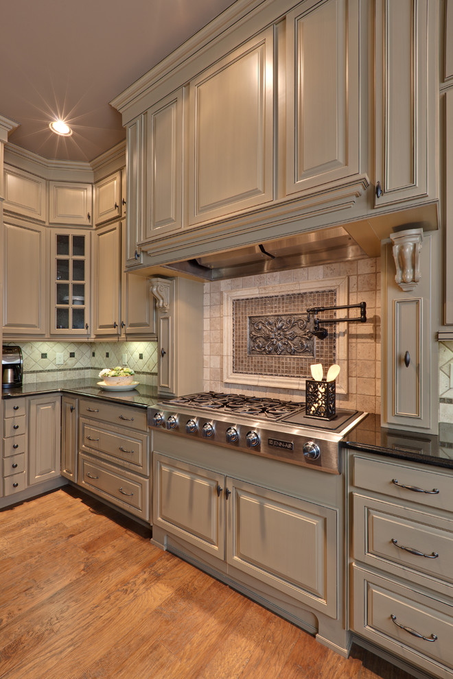 Example of a classic kitchen design in Atlanta with raised-panel cabinets, beige cabinets, beige backsplash and stainless steel appliances