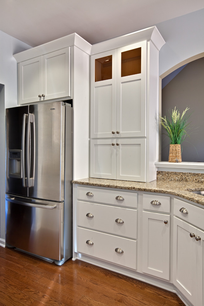 Diseño de cocina contemporánea, pequeña, con armarios estilo shaker, puertas de armario blancas, electrodomésticos de acero inoxidable, fregadero de doble seno, encimera de granito, suelo de madera en tonos medios, península, suelo marrón y encimeras beige