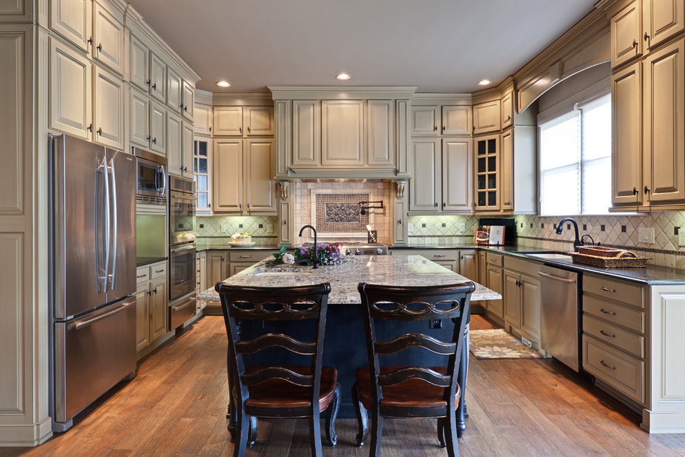 Elegant u-shaped kitchen photo in Atlanta with stainless steel appliances, granite countertops, raised-panel cabinets and beige cabinets
