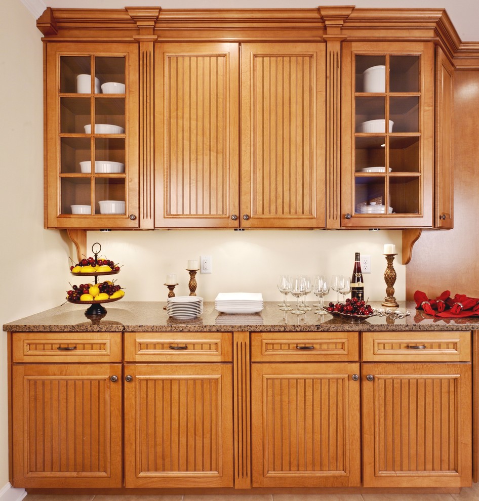 Inredning av ett klassiskt stort brun brunt kök och matrum, med luckor med glaspanel, skåp i mellenmörkt trä, granitbänkskiva, rostfria vitvaror, travertin golv och beiget golv