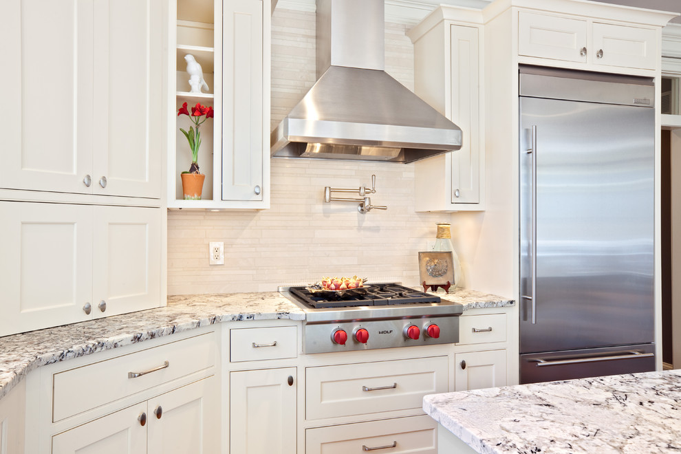 Moderne Küche mit Küchengeräten aus Edelstahl, Granit-Arbeitsplatte, Kassettenfronten, weißen Schränken, Küchenrückwand in Beige und Rückwand aus Travertin in Atlanta