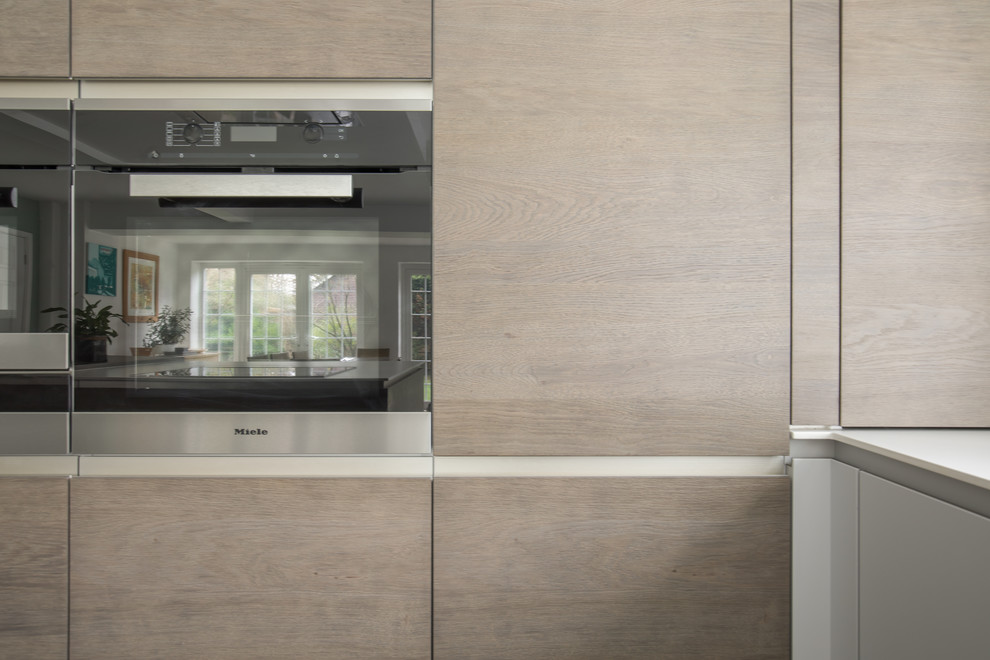 Esempio di una cucina minimal di medie dimensioni con lavello integrato, ante lisce, ante in legno scuro, top in superficie solida e elettrodomestici da incasso