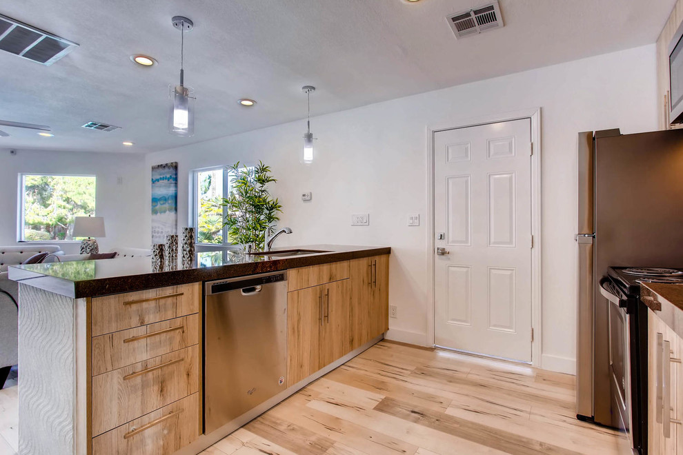 Exempel på ett litet modernt brun linjärt brunt kök med öppen planlösning, med en rustik diskho, släta luckor, skåp i ljust trä, stänkskydd i sten, rostfria vitvaror, en halv köksö och grått golv