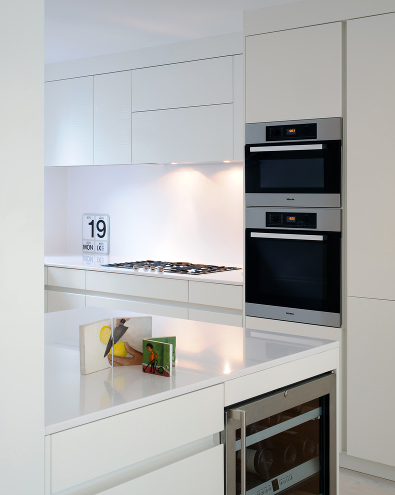 Mittelgroße Skandinavische Küche in L-Form mit Küchenrückwand in Weiß, Küchengeräten aus Edelstahl, hellem Holzboden und Kücheninsel in London