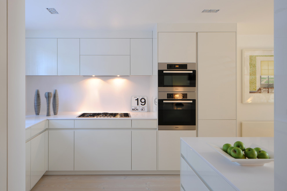 Mittelgroße Nordische Küche in L-Form mit Küchenrückwand in Weiß, Küchengeräten aus Edelstahl, hellem Holzboden und Kücheninsel in London