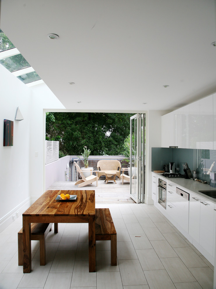 Immagine di una cucina scandinava con ante lisce, ante bianche, paraspruzzi blu, paraspruzzi con lastra di vetro, elettrodomestici in acciaio inossidabile e pavimento con piastrelle in ceramica
