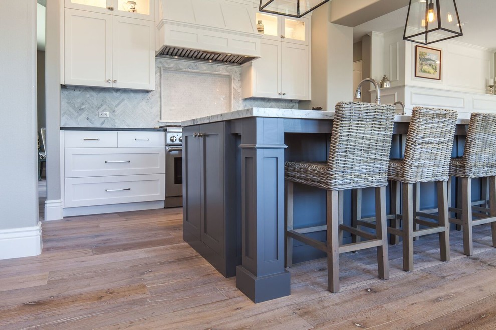 Mid-sized beach style u-shaped medium tone wood floor eat-in kitchen photo in San Diego with a double-bowl sink, raised-panel cabinets, white cabinets, marble countertops, gray backsplash, marble backsplash, stainless steel appliances and an island