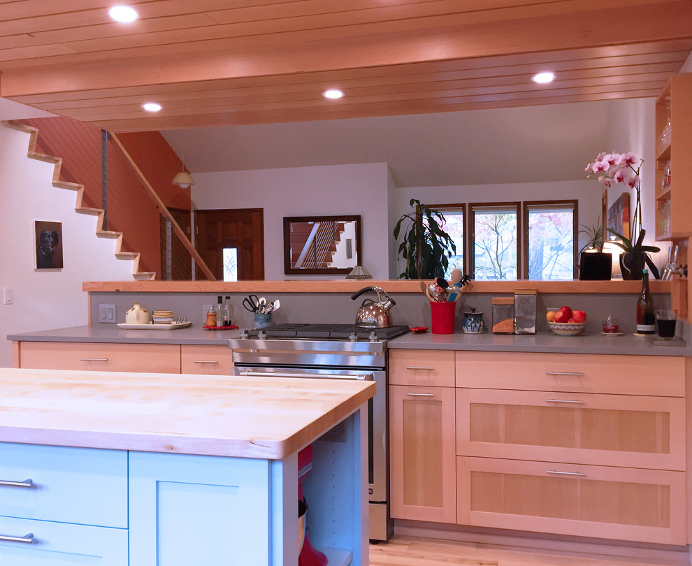 Foto på ett mellanstort funkis kök, med en undermonterad diskho, släta luckor, skåp i ljust trä, bänkskiva i kvarts, grått stänkskydd, rostfria vitvaror, ljust trägolv och en köksö