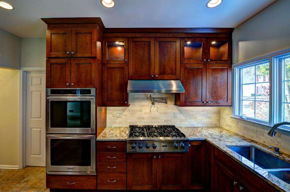 Exempel på ett stort klassiskt kök, med en undermonterad diskho, skåp i shakerstil, skåp i mellenmörkt trä, granitbänkskiva, beige stänkskydd, stänkskydd i tunnelbanekakel, rostfria vitvaror, klinkergolv i porslin och en köksö