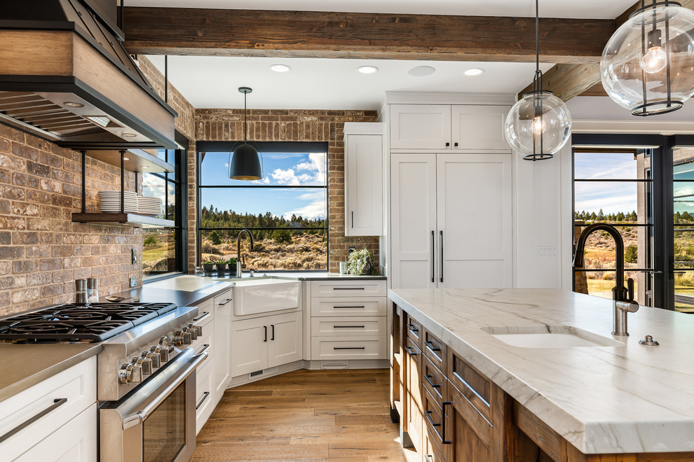 Inspiration for a mid-sized country u-shaped painted wood floor and brown floor eat-in kitchen remodel in Other with a farmhouse sink, recessed-panel cabinets, white cabinets, quartzite countertops, brown backsplash, brick backsplash, stainless steel appliances, an island and white countertops