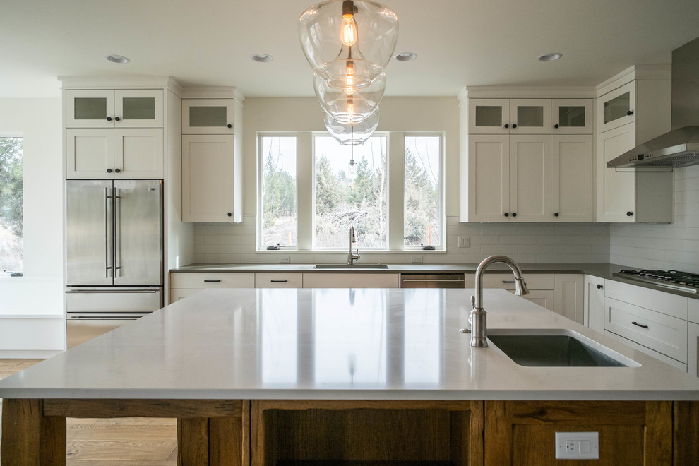 Mid-sized elegant l-shaped medium tone wood floor eat-in kitchen photo in Other with an undermount sink, shaker cabinets, white cabinets, quartz countertops, white backsplash, subway tile backsplash, stainless steel appliances and an island