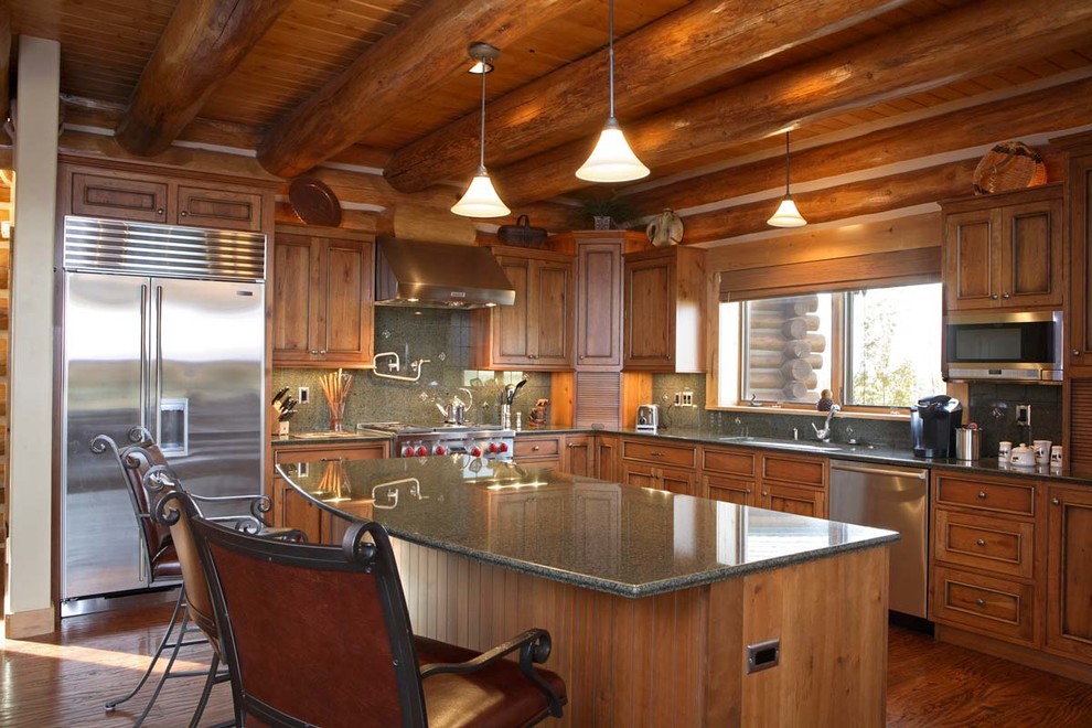 Exempel på ett stort rustikt l-kök, med en undermonterad diskho, luckor med upphöjd panel, skåp i mellenmörkt trä, grått stänkskydd, rostfria vitvaror, mellanmörkt trägolv, en köksö och brunt golv