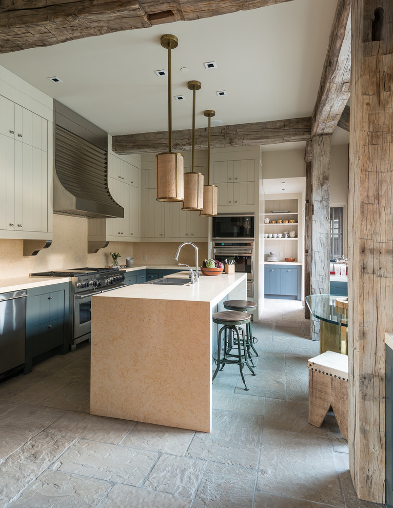 Mittelgroße Rustikale Küche mit Doppelwaschbecken, beigen Schränken, Granit-Arbeitsplatte, Kalkstein und Kücheninsel in Sonstige