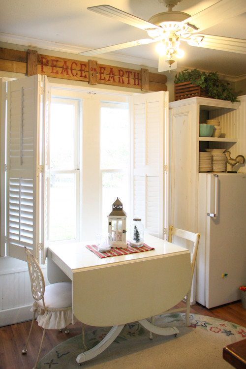 Esempio di una cucina parallela country chiusa e di medie dimensioni con ante a filo, ante bianche, paraspruzzi bianco, elettrodomestici bianchi e pavimento in legno massello medio