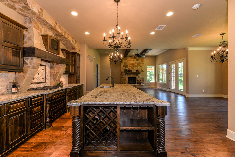 Foto på ett stort rustikt kök med öppen planlösning, med en undermonterad diskho, luckor med upphöjd panel, skåp i mörkt trä, granitbänkskiva, vitt stänkskydd, stänkskydd i stenkakel, rostfria vitvaror, mörkt trägolv och en köksö