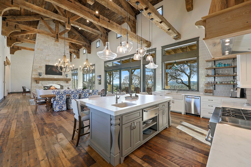 Mountain style u-shaped medium tone wood floor and brown floor kitchen photo in Austin with an undermount sink, recessed-panel cabinets, white cabinets, white backsplash, stainless steel appliances and an island