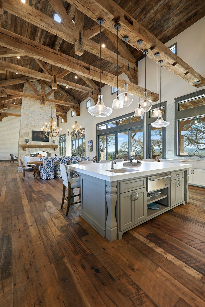 Photo of a rustic u-shaped kitchen in Austin with a submerged sink, recessed-panel cabinets, white cabinets, white splashback, stainless steel appliances, medium hardwood flooring, an island and brown floors.